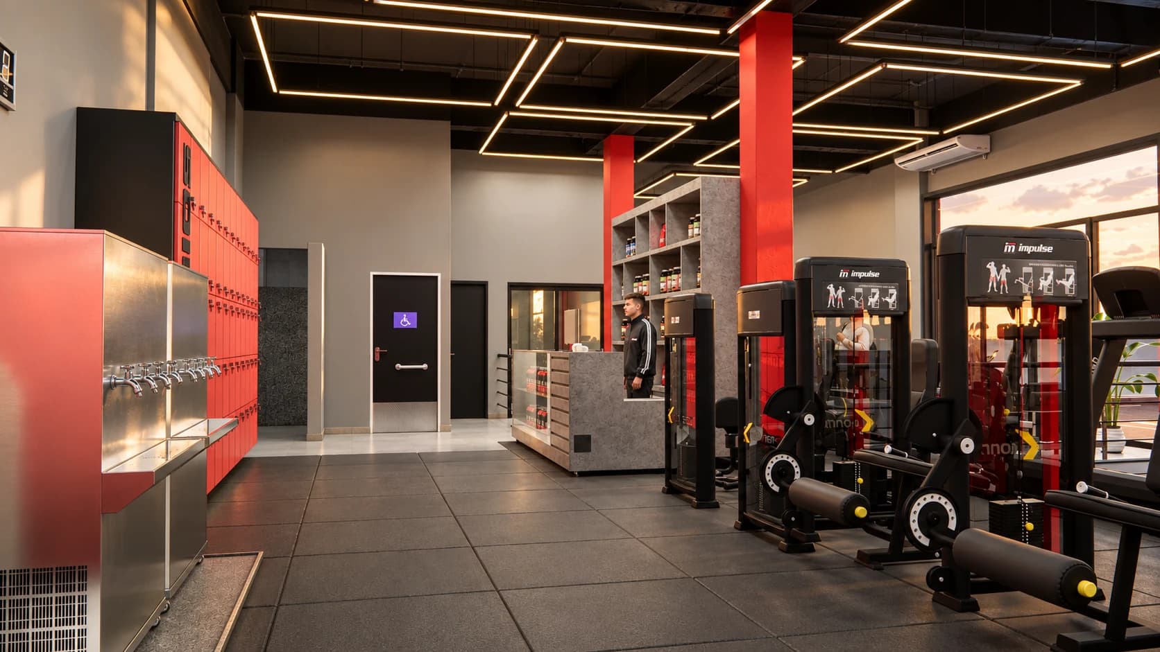 Interior da futura Insano Academia Cidade Nova: armários vermelhos, bebedouros, balcão de recepção com suplementos e aparelhos de musculação